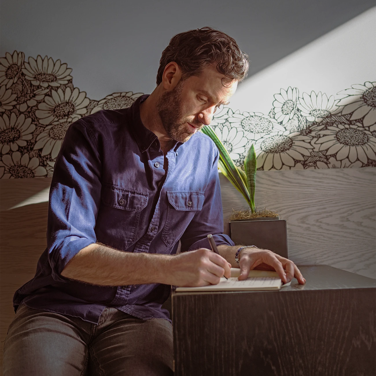 Jason writing in a notebook, a beam of sunshine streaming down